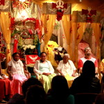 Foto ilustrando um diálogo entre pessoas, composto por quatro mulheres e dois homens, onde todos estão em um palco falando ao público.