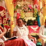Foto ilustrando um diálogo entre pessoas, onde á esquerda á uma mulher com um microfone na mão ,e a direita da imagem há duas mulheres negras .