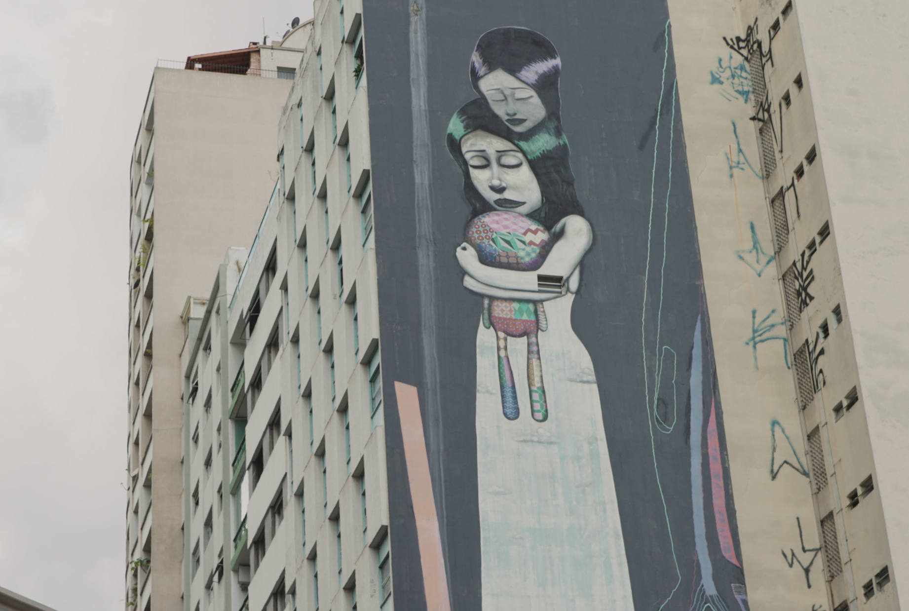 Mural em um muro da cidade de São Paulo, onde uma mãe está abraçada com sua filha